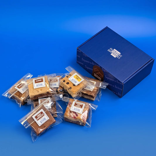 Individually wrapped brownies, brookies and a chocolate chip blondie beside a closed blue Buckabee Brownies box.