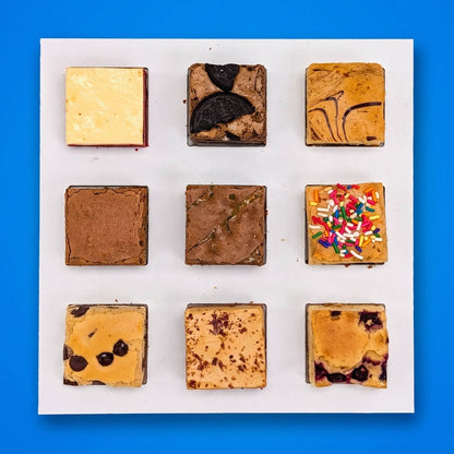 Buckabee Build Your Own Box — nine assorted brownies and blondies in a 3x3 grid on a white board, featuring Oreo, peanut butter, confetti, and raspberry flavors