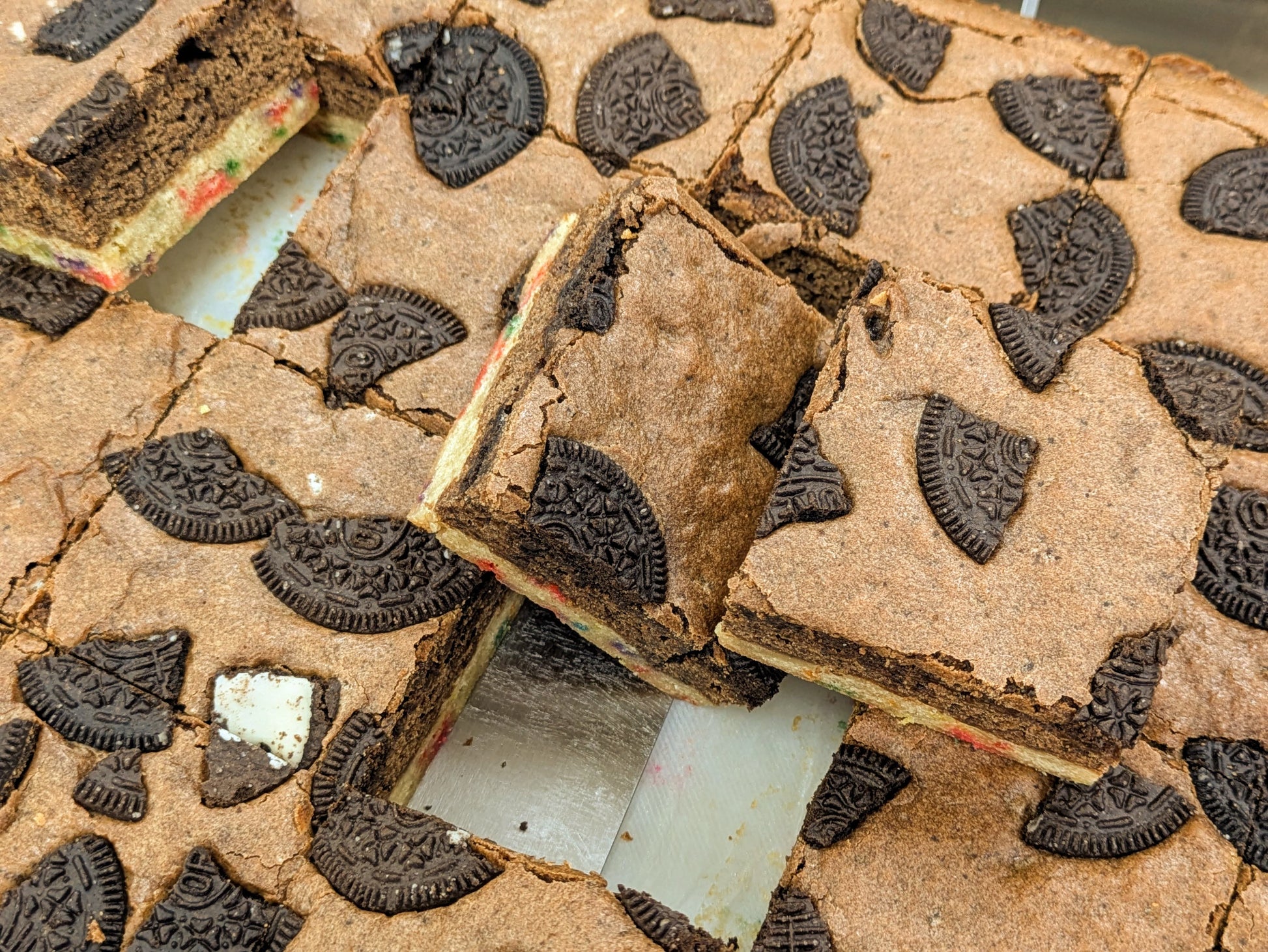 Overhead view of a full pan of Cookies, Cream & Confetti Brookies from Buckabee Brownies, topped with Oreo cookies and cut into XL squares