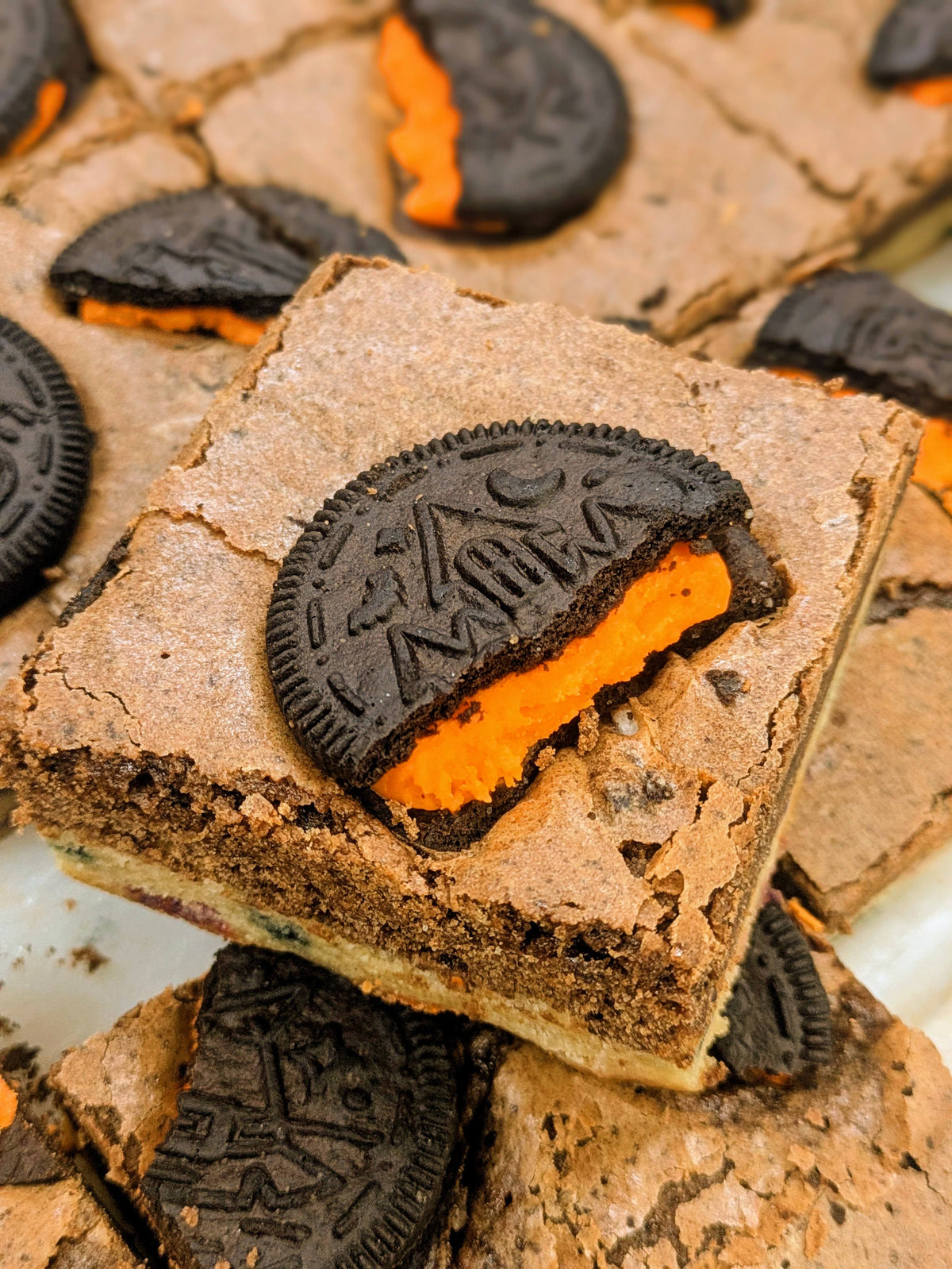 Cookies and Cream brownie topped with Halloween Oreo cookies and Confetti bottom layer, with one Oreo open to reveal a bright orange cream filling for Halloween.