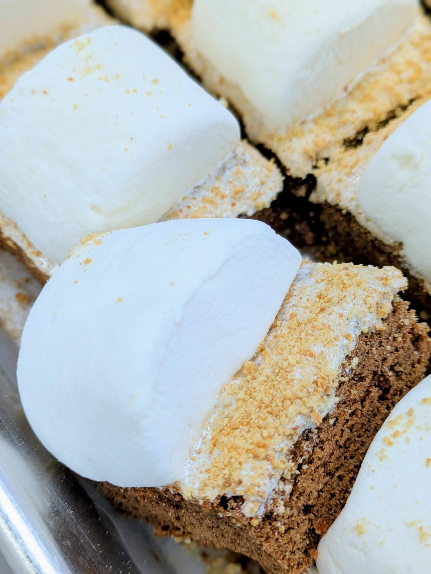 Close-up of Smores Brownie topped with large white marshmallows and a crumbly golden-brown graham crackers