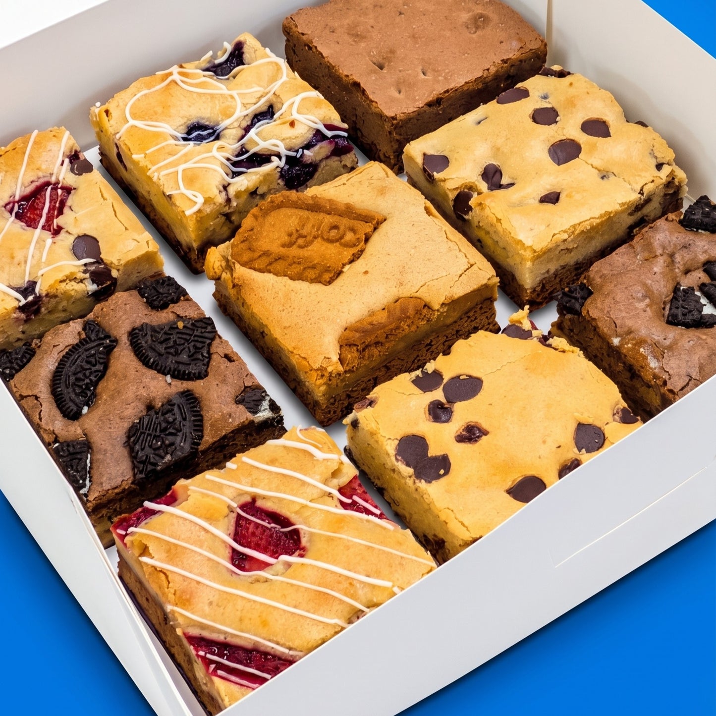 Close-up angled view inside a Build Your Own Large Box showing nine large brookies and brownies with toppings including Oreo cookies, strawberry drizzle, biscoff, and chocolate chips