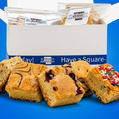 Buckabee Brownies' The Buttery Blondies Shipped Box with several blondies displayed in front on a bright blue background. The blondies include chocolate chips, raspberries, and sprinkles.