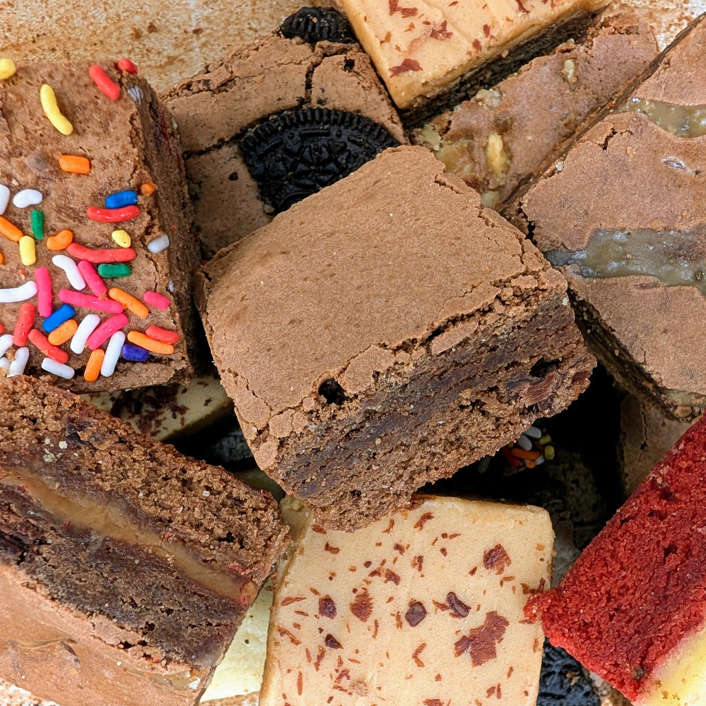 Assorted chocolate brownies with different toppings on a metal tray
