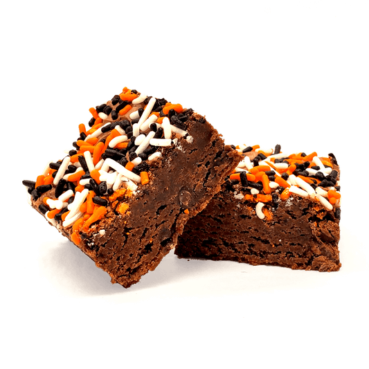 Two chocolate brownies topped with orange, white, and black sprinkles, photographed on a clean white background.